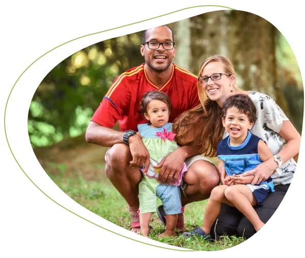 A family posing for the camera in front of some trees.