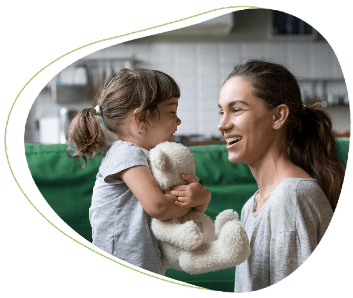 Child and woman smiling with a teddy bear.